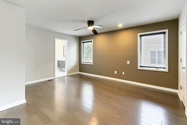 unfurnished room featuring dark wood finished floors, baseboards, and a ceiling fan