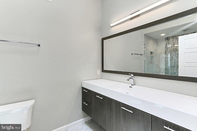 bathroom with toilet, vanity, baseboards, and a stall shower