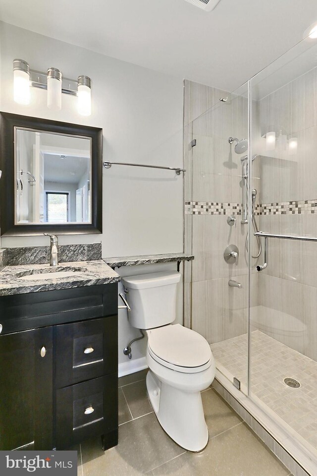 bathroom with tile patterned floors, vanity, a tile shower, and toilet