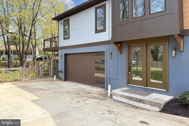 exterior space featuring concrete driveway, a garage, fence, and stucco siding