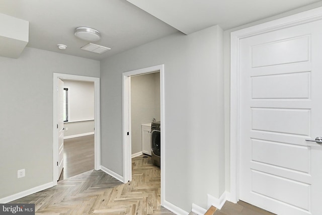 hallway featuring baseboards, visible vents, and washer / dryer