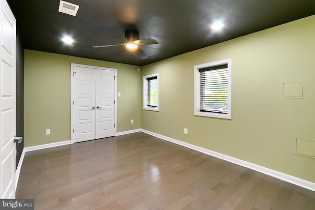 unfurnished bedroom featuring visible vents, baseboards, a closet, a ceiling fan, and wood finished floors