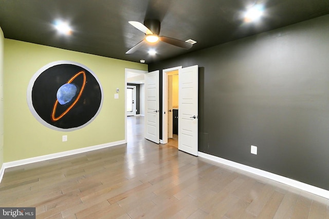 empty room featuring ceiling fan, wood finished floors, and baseboards