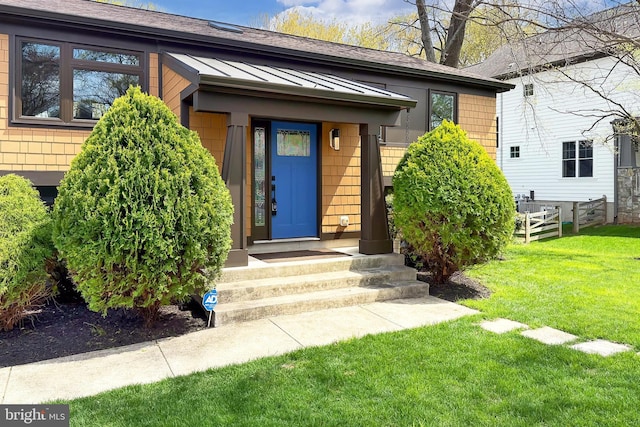 property entrance with a standing seam roof, a yard, and metal roof