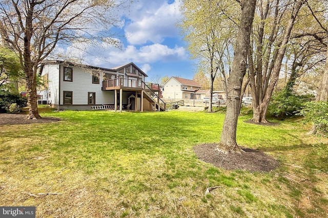rear view of property featuring stairway, a wooden deck, and a lawn