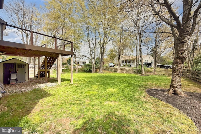 view of yard featuring a storage shed, an outdoor structure, fence, stairs, and a deck