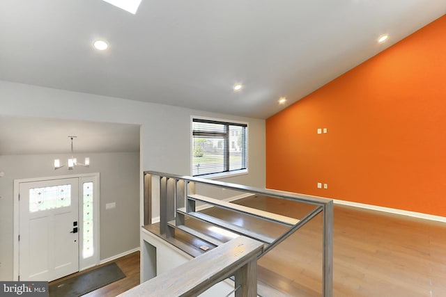 entrance foyer with recessed lighting, a notable chandelier, wood finished floors, and lofted ceiling