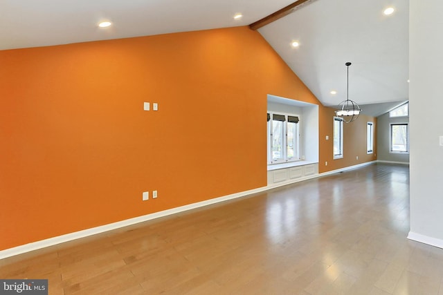 unfurnished living room with a chandelier, plenty of natural light, baseboards, and beam ceiling