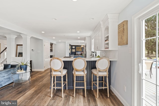 kitchen with tasteful backsplash, white cabinets, light countertops, baseboards, and dark wood-style floors