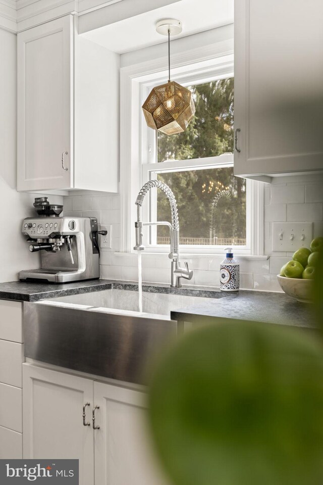 kitchen featuring pendant lighting, decorative backsplash, dark countertops, and white cabinetry