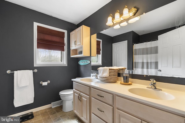 full bath featuring double vanity, baseboards, a sink, and toilet