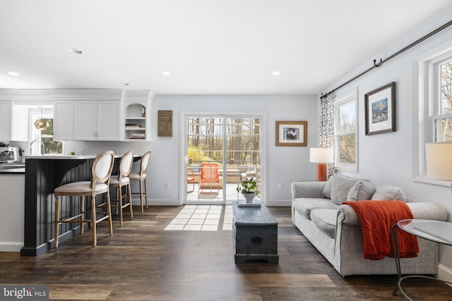 living room featuring a wealth of natural light, recessed lighting, and dark wood-type flooring