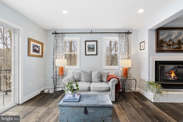 living room with a glass covered fireplace, recessed lighting, baseboards, and dark wood finished floors