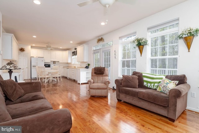 living area featuring light wood-type flooring, a ceiling fan, and recessed lighting