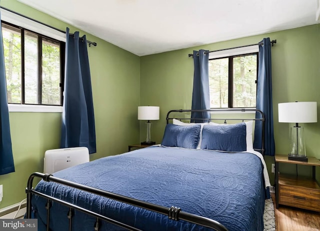 bedroom featuring wood finished floors and a baseboard heating unit