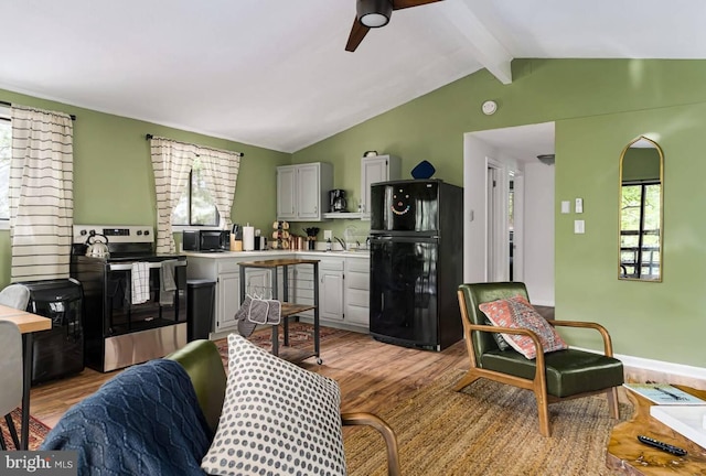 living room featuring ceiling fan, light wood finished floors, lofted ceiling with beams, and baseboards