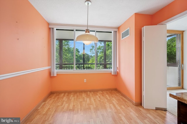 unfurnished dining area with light wood-style flooring and baseboards