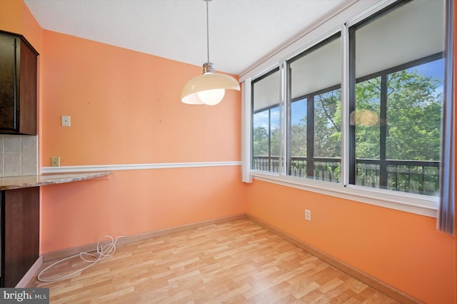 unfurnished dining area featuring light wood-type flooring and baseboards