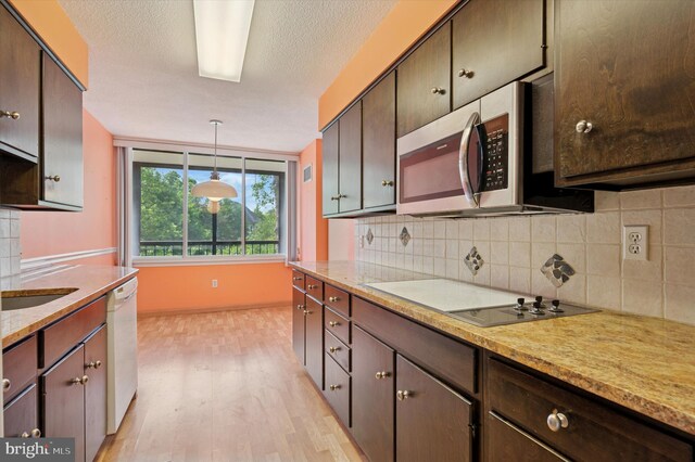 kitchen with stainless steel microwave, electric stovetop, light wood-style floors, decorative backsplash, and dishwasher