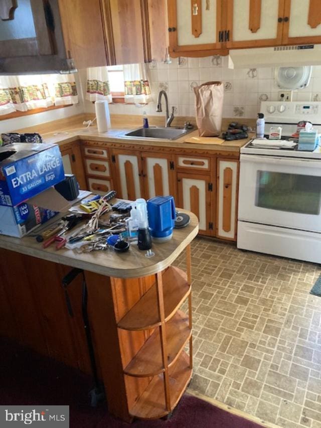 kitchen featuring a sink, light countertops, under cabinet range hood, decorative backsplash, and electric range
