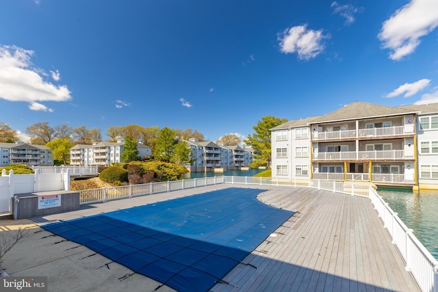 pool with a residential view, fence, and a water view