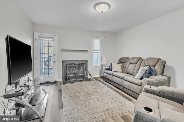 living area with a wealth of natural light, wood finished floors, and a fireplace with flush hearth