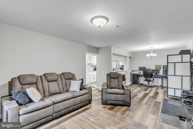 living room with baseboards, an inviting chandelier, and light wood-style floors