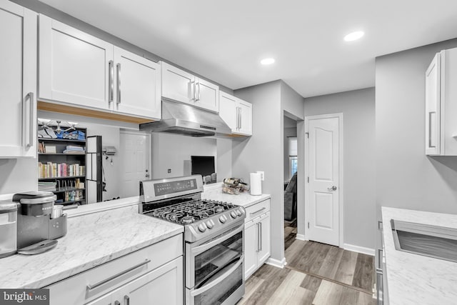 kitchen featuring white cabinetry, double oven range, light wood-style floors, and under cabinet range hood