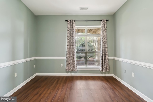 empty room with baseboards, wood finished floors, and visible vents