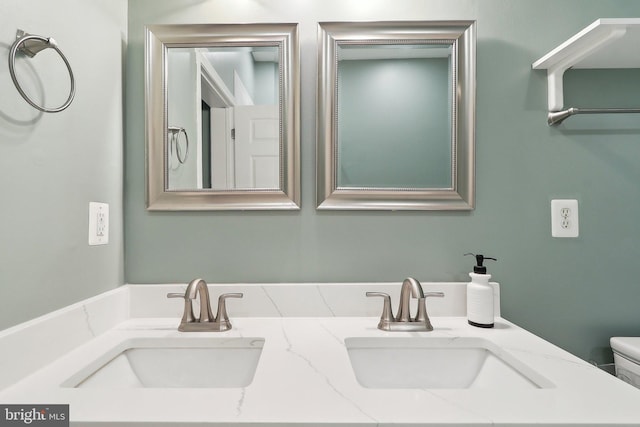 bathroom featuring double vanity, toilet, and a sink