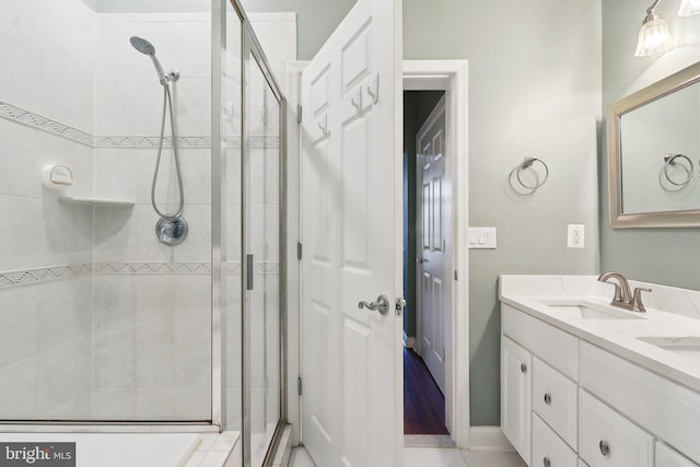 bathroom featuring double vanity, a shower stall, and a sink
