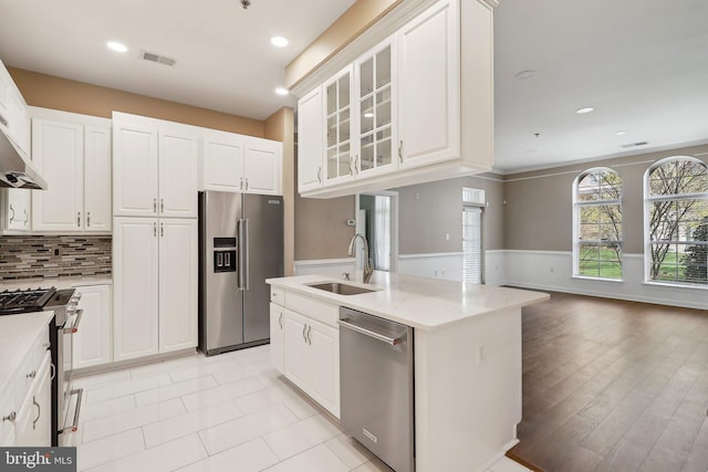 kitchen featuring a sink, a wainscoted wall, appliances with stainless steel finishes, white cabinetry, and visible vents