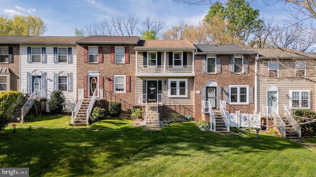 back of house with a lawn, brick siding, and a balcony