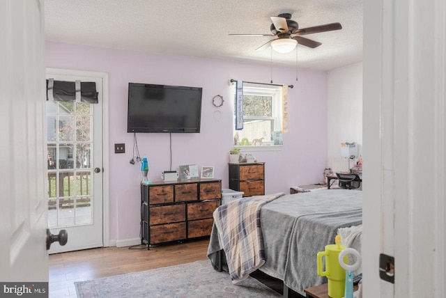 bedroom with a ceiling fan, wood finished floors, and a textured ceiling