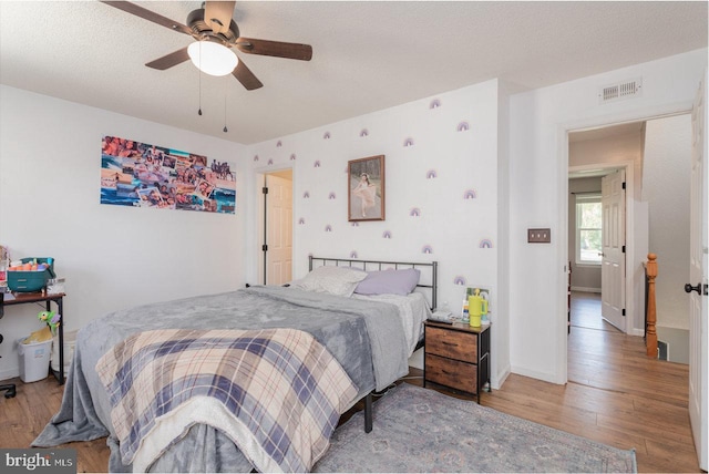 bedroom with baseboards, wood finished floors, visible vents, and ceiling fan