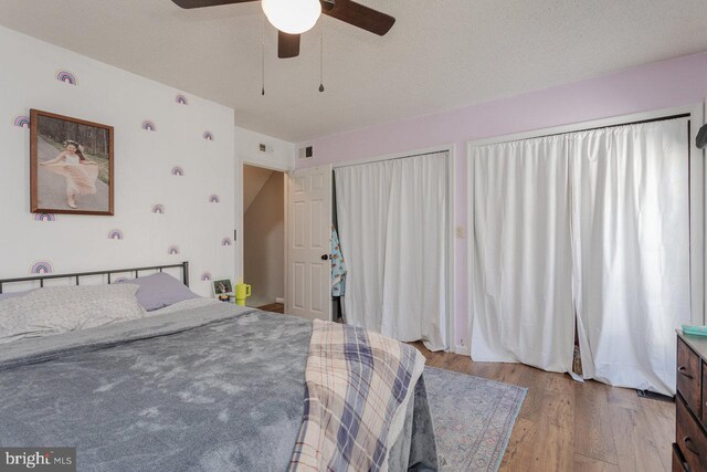 bedroom featuring a ceiling fan, light wood-style floors, visible vents, and a textured ceiling