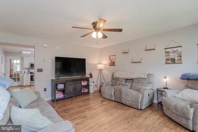 living area with light wood finished floors, baseboards, and ceiling fan