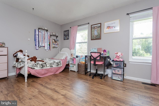 bedroom with wood finished floors, visible vents, and baseboards