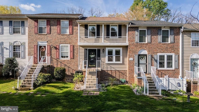 townhome / multi-family property featuring brick siding, a front yard, and a balcony