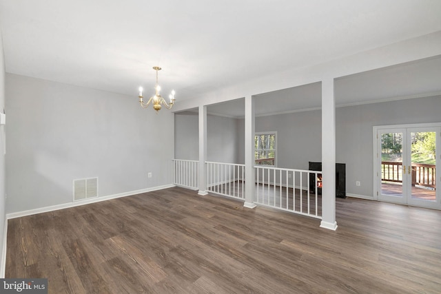 spare room featuring baseboards, an inviting chandelier, dark wood-style floors, crown molding, and visible vents