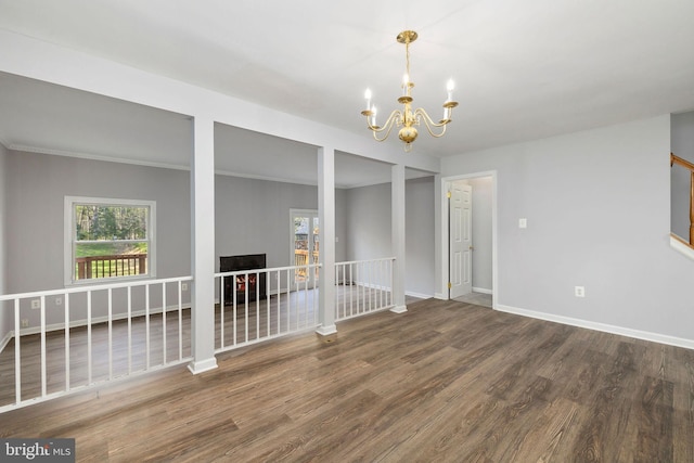 empty room featuring a chandelier, wood finished floors, baseboards, and a wealth of natural light