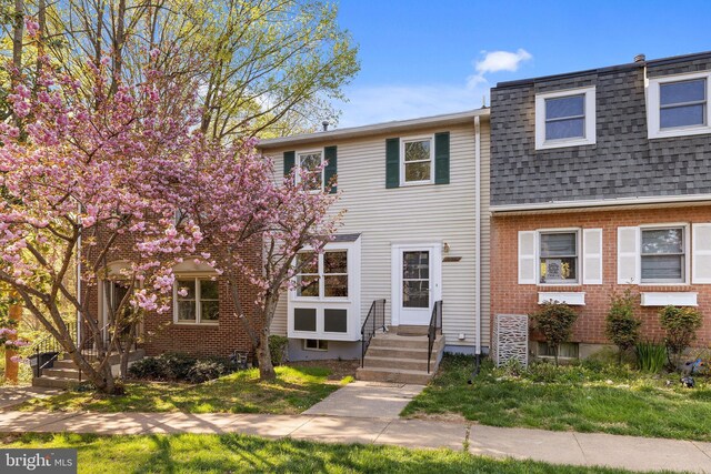 multi unit property with roof with shingles, mansard roof, entry steps, and brick siding