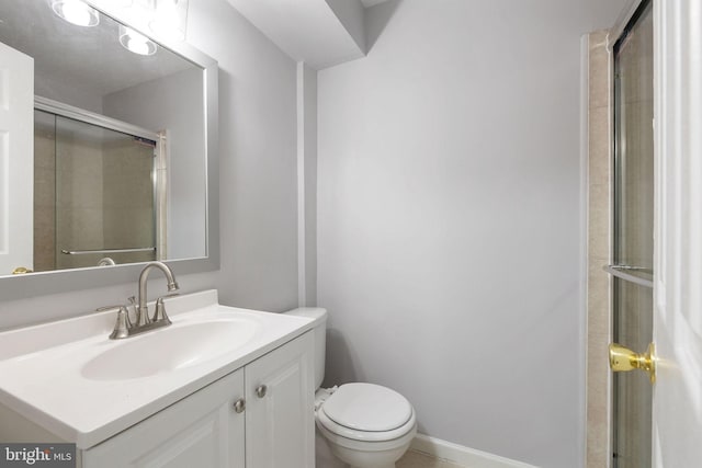bathroom featuring toilet, a shower with shower door, vanity, and baseboards