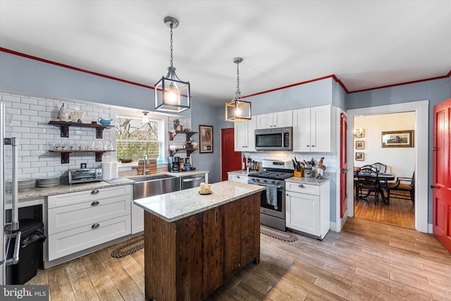 kitchen featuring light wood-type flooring, white cabinets, a kitchen island, appliances with stainless steel finishes, and decorative backsplash