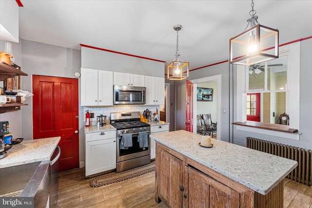 kitchen with light wood-style floors, radiator, white cabinetry, stainless steel appliances, and backsplash