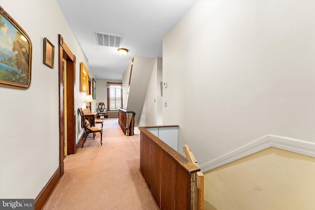 hallway featuring light carpet, an upstairs landing, visible vents, and baseboards