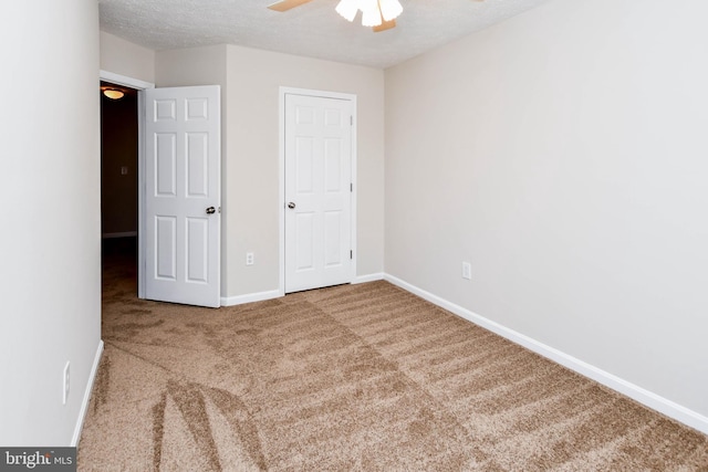 unfurnished bedroom featuring a ceiling fan, baseboards, carpet, and a textured ceiling