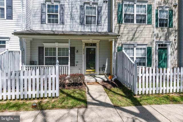 view of front of house with a shingled roof, covered porch, and fence