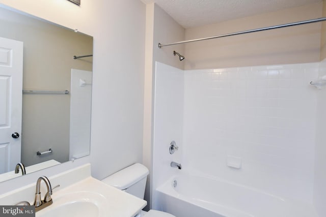 full bath featuring bathing tub / shower combination, vanity, a textured ceiling, and toilet