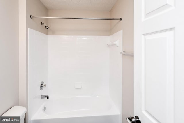 bathroom with bathing tub / shower combination, a textured ceiling, and toilet
